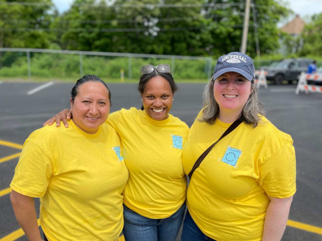 3 woman wearing yellow shirts smiling to the camera
